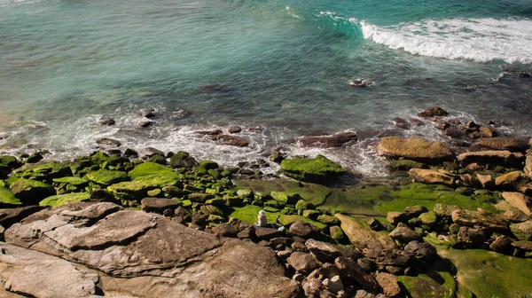 シドニー ニューサウスウェールズ州 オーストラリアのボンダイビーチの岩の海岸線に座っている一人の人物 — ストック写真