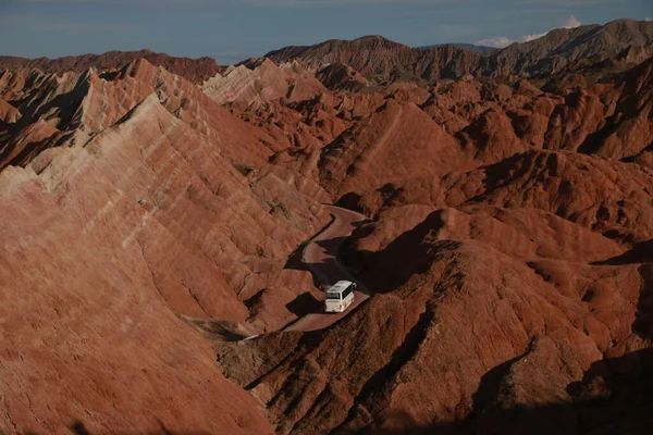 从空中俯瞰一辆白色的公共汽车穿过红色的岩石山 — 图库照片