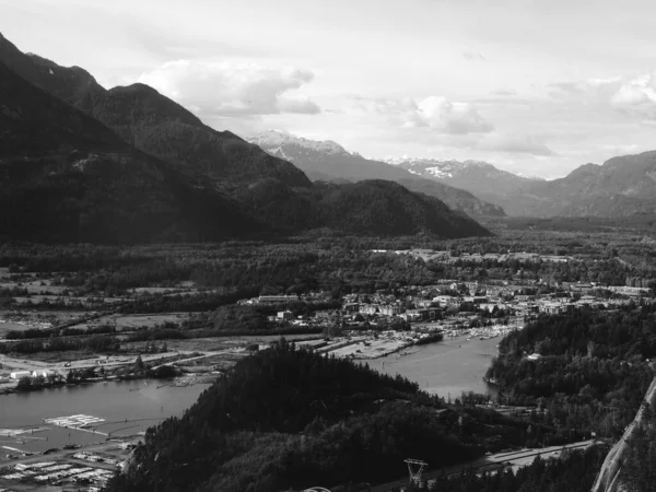 山中小河边一座城镇的灰蒙蒙的照片 位于山谷中央 被群山环绕 — 图库照片
