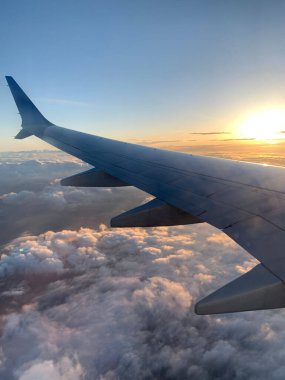 Gün doğumunda bulutların üzerinde uçan bir kanadın güzel bir görüntüsü.