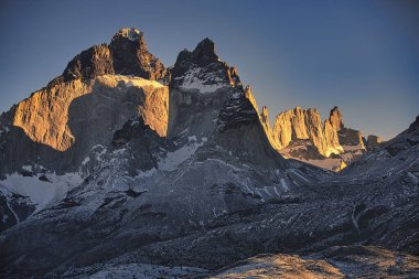 Güneşli bir günde açık bir gökyüzüne karşı kocaman kayalık bir dağ.