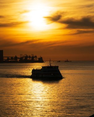 Gün batımında denizde yüzen bir geminin silüeti.