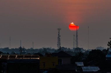Gün batımında binalardan ve elektrik direklerinden oluşan bir siluet.