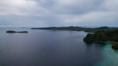 Bulutlu gökyüzünün altında, Filipinler kıyısında huzurlu bir su manzarası.