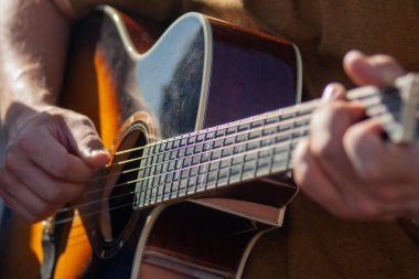 Gitar çalan bir erkeğin yakın plan fotoğrafı.