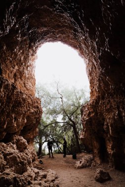 Mağaranın kemerli girişinde iki turist var.
