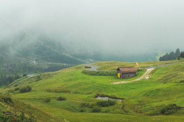 Yeşil vadideki kırsal ahşap kulübe sisli yamaçlara karşı..