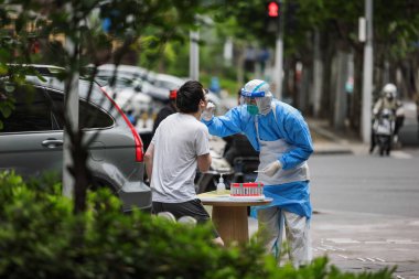 PPE 'de bir sağlık çalışanı salgın sırasında Şangay sokaklarında COVID testleri yapıyor.