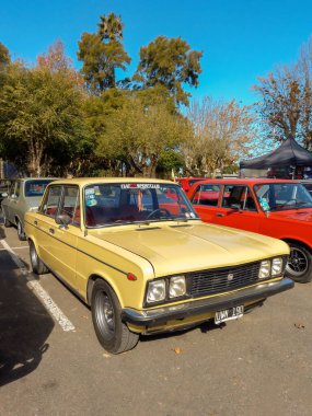 Eski sarı Fiat 125 dört kapılı sedan 1970 'ler bir parkta. Güneşli bir gün. Doğa, ağaçlar. Klasik araba şovu. Kopyalama alanı