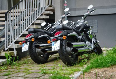 İki Suzuki motosikleti bir merdivenin yanına park etmiş..