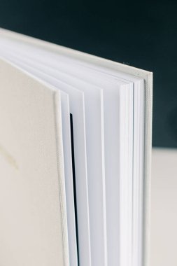 Bulanık bir arkaplanda beyaz minimalist kapağı olan bir fotoğraf albümü ya da düğün albümünün yakın çekimi