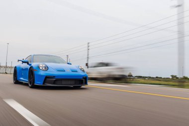 Süper hızlı bir Porsche GT3992 Carrera köpekbalığı mavi spor arabasının caddede sürüşü.