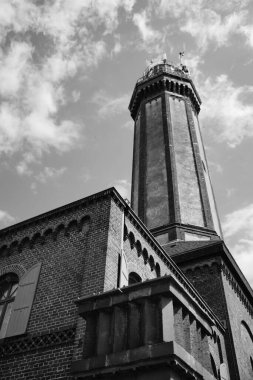 Niechorze, Polonya 'daki Deniz fenerinin bulutlu gökyüzü arka planına karşı gri ölçekli düşük açılı görüntüsü.