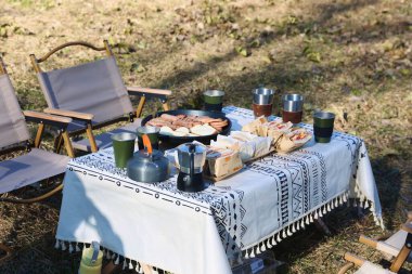 Sandviçler ve sosislerle kahvaltı masasının yakın çekimi.