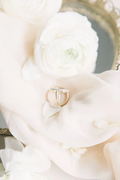 パステルピンクのシルク素材と花の装飾でエレガントなミニマリストの結婚指輪のトップビュー — ストック写真
