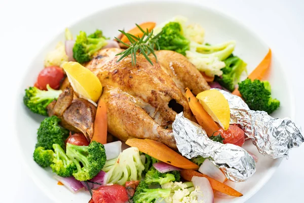 Beyaz tabakta sebzeli kızarmış bir tavuğun yakın plan fotoğrafı.