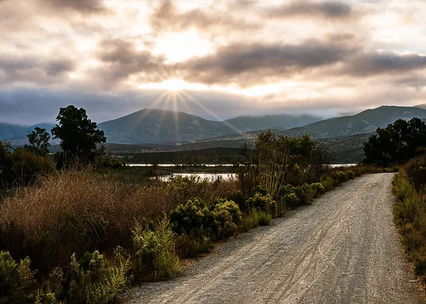 Uma Estrada Terra Com Montanhas Fundo Pôr Sol Cênico — Fotografia de Stock