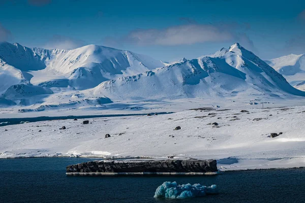 斯瓦尔巴岛附近被雪覆盖的山脉 陆地边缘有一个未被发现的岩层 海洋中有一个浅蓝色的冰层 — 图库照片