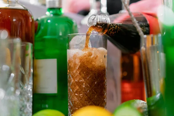 Seseorang Menuangkan Soda Dalam Gelas Penuh Antara Botol Botol Alkohol — Stok Foto