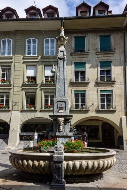 Kramgasse caddesindeki bir fıskiyenin dikey görüntüsü Bern şehir merkezindeki bir binanın önünde.