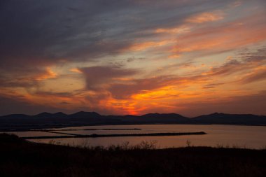 Gün batımında göl ve dağların kıyısı.