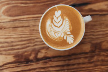 Ahşap bir arka planda fincanda latte sanatının en üst görüntüsü.