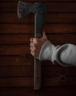 Tahta bir duvara balta tutan bir elin dikey yakın çekimi.