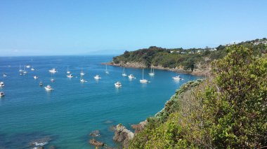 Mavi gökyüzü arka planında okyanusta seyreden birkaç gemi ve teknenin manzarası.