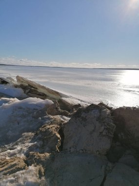 Güneşli bir kış gününde arka planında soğuk deniz olan kayalık bir kıyı şeridi.