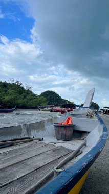 Mavi bulutlu arka planda, kıyıya yakın boş bir teknede bir sepet.