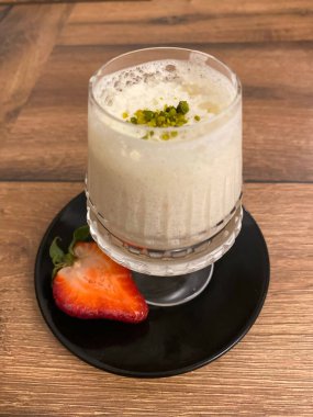 Çilekli bir bardak beyaz smoothie 'nin dikey yakın çekimi.