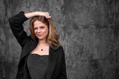 Stüdyoda saçlarını tutan zarif siyah elbiseli çekici bir beyaz kız.