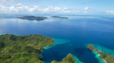 Güneşli bir günde mavi bulutlu bir gökyüzünün altında Filipinler 'deki güzel bir tropikal adanın hava aracı görüntüsü.