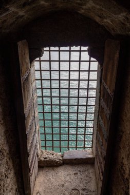 Ortaçağ Chillon Kalesi 'ndeki kare metal parmaklıklı pencereden Cenevre Gölü manzarası.