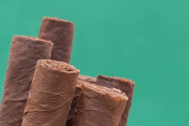 Yeşil arka planda koyu kahverengi puroların yakın çekimi.