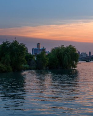 Gün batımında ağaçlarla çevrili bir gölün dikey görüntüsü.