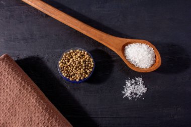 Siyah bir arka planda ahşap bir kaşık tuzun yakın çekimi.