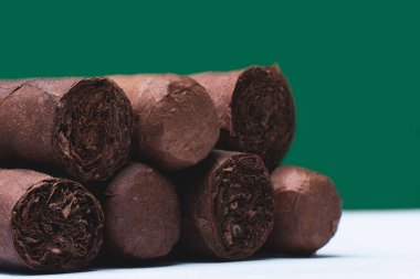 Yeşil arka planda koyu kahverengi puro yığınının yakın çekimi.