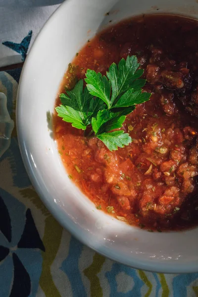 Red salsa in serving bowl with green parsley garnish