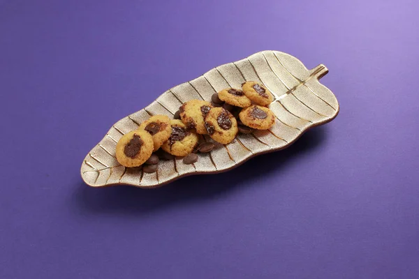 チョコレート充填クッキーは葉の形で装飾的なプレートに配置されています ライラックの背景においしいデザートの珍味 — ストック写真