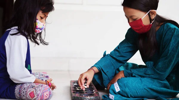 两个戴面具的小女孩在玩一种叫做达肯的传统的印度尼西亚儿童游戏 — 图库照片