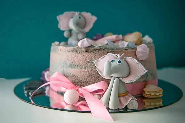 A closeup of a cake with cute elephant figures for a girl kid\'s birthday