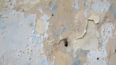 Üzerinde delikler olan eski kirli bir duvarın yakın çekimi..