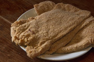 Masanın üzerinde pişmemiş şnitzel tabağının yakın çekimi.