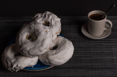 Kahve fincanlı şekerli çörek ve siyah arka planda metal çaydanlık.