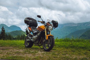 Yeşillik dağlarının arkasına park etmiş bir motosiklet.