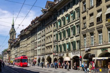 Heiliggeistkirche, Kutsal Ruh Kilisesi ve İsviçre 'nin Bern şehrinde kırmızı tramvayla yürüyen insanların olduğu güzel bir cadde.