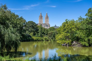 San Remo kulesi Central Park 'a karşı yoğun yeşil ağaçlar ve New York' ta yansıması olan bir göl.