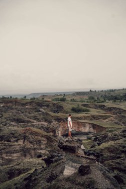 Kayanın üzerinde duran ve Tatacoa Çölü 'nün manzarasının keyfini çıkaran adamın dikey görüntüsü. Kolombiya.