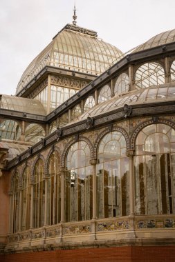 İspanya, Madrid 'deki Retiro Park' ta bulutlu bir gökyüzüne karşı güzel bir binanın dikey görüntüsü.